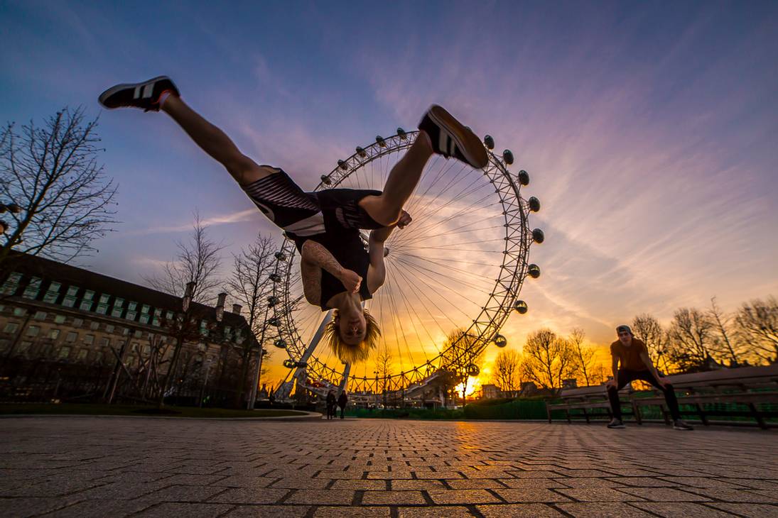 young man flipping in front of a ferris wheel